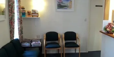 The waiting room: chairs, a sofa, pamphlets on a shelf and a painting on the wall